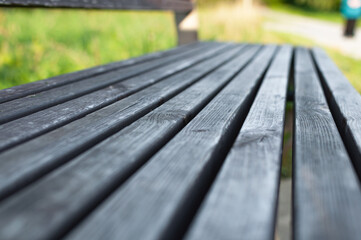 Wooden park bench in the garden. Macro details. Selective focus. Blurred wooden texture. Detail of furniture. Bench in park. Wooden dry bench in summer.