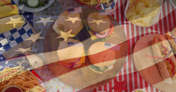 Image of flag of united states of america moving over festive snacks, hotdogs and burgers