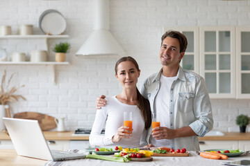 Healthy couple with juice preparing lunch together in kitchen at home