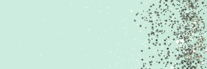 Banner with glowing silver colored glittering stars confetti scattered on a turquoise background with place for text.