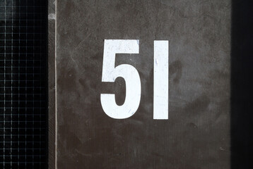 Close Up of White Painted Number 51 on Smooth Wooden Door 
