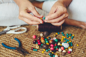 People at home with work or hobby job activity. Close up of woman hands making cheap jewelry to...