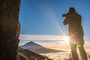 Standing man take professional photography of a beautiful sunset at the mountains - concept of freedom and travel lifestyle with adventure and exploring places - happy people enjoying nature