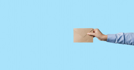 Woman's hand holding closed envelope against blue background
