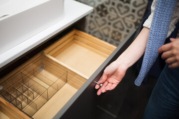 girl looks at drawer. selects furniture and accessories for storage in bathroom