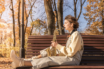 teen girl sitting on a park bench playing the saxophone