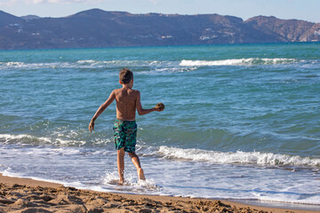 happy boy throws sand on the seashore during a storm, horizontal