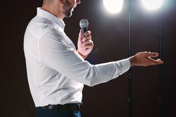 Motivational speaker with microphone performing on stage, closeup