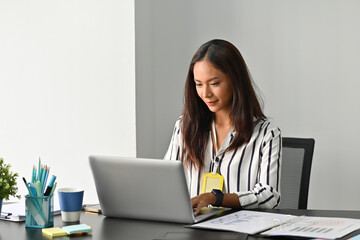 Photo of a young business owner working at the working desk surrounded by a computer laptop, paperwork and office equipment.