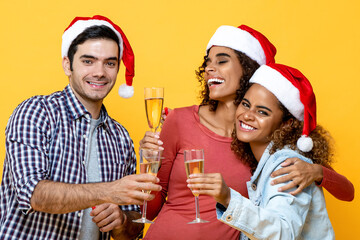 Group of three diverse friends celebrating Christmas drinking champagne together on yellow studio background