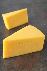 Two pieces of hard cheese on textured background