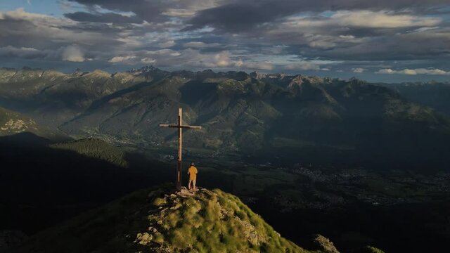 Mann am Gipfelkreuz in den Alpen im Sommer / Herbst.  Südtirol