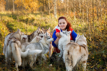 The dog breeder with her husky dogs in autumn forest