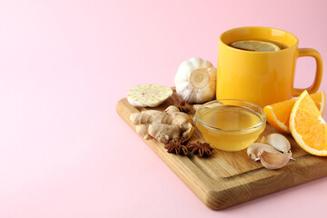 Concept of treatment colds with honey and garlic on pink background