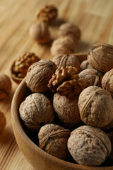 Walnuts in wooden bowl on wooden background