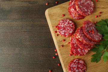 Сoncept of tasty food with salami sausage on wooden background