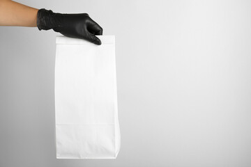 Woman holding paper bag on white background, closeup. Space for text