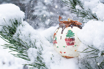 A colorful Christmas ball hung on a snow-covered Christmas tree twig 