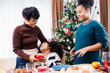 African American family surprising together with a gift on Christmas day while dinner. Merry Christmas. Happy family.