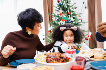 Happy family are having dinner at home. Celebration holiday and togetherness near Christmas tree. African American family. Merry Christmas.