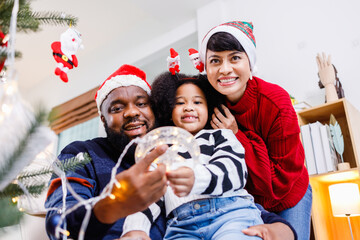 African American family help decorate the Christmas tree at home. Merry Christmas.