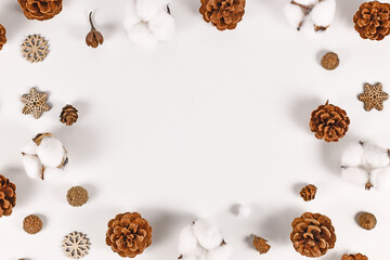 Winter arrangement with fir cones, snowflake ornaments and cotton Gossypium bolls forming frame around white background