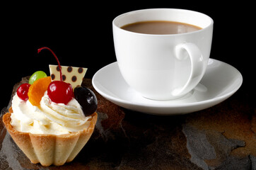 cup of coffee and delicious cake on black background