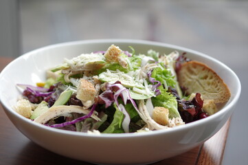 Caesar salad with avocado, shredded cheese and slices of chicken breast