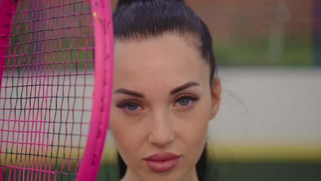  Portrait Of Attractive Brunette Female Tennis Player With Vintage Pink Racket Outdoor. Pretty Model With Beautiful Big Bright Blue Eyes Holding Racket. Sports Training At An Outdoor Urban Court