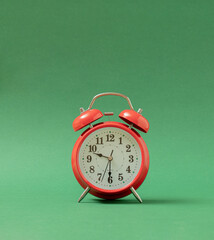 old red vintage table clock against pastel green background with shadow. Retro abstract art