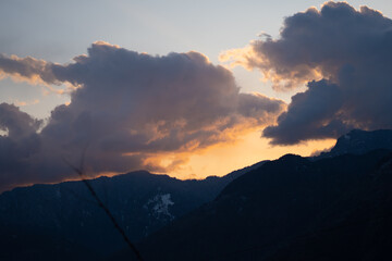 Orange clouds above the snow covered mountains of Kullu Valley during the sunset at Kullu in Himachal Pradesh, India. Beautiful sunset above the mountains besides Kullu in Himachal Pradesh, India.