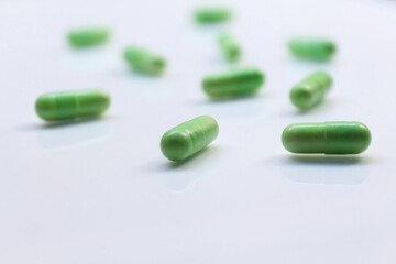 Obraz na płótnie Canvas green pills on white background. Selective focus, blurred background