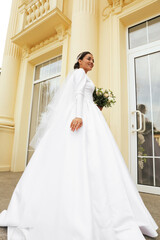 Fototapeta premium Young bride wearing wedding dress with beautiful bouquet outdoors
