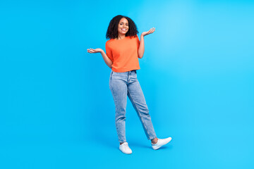 Full body photo of young cheerful african woman happy positive smile hesitate doubt think isolated over blue color background