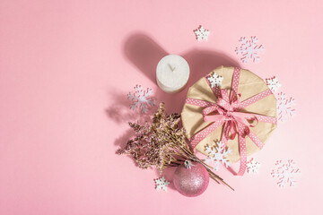 Christmas or New Year gift concept in pink tones. Wrapper box, tied bow, flowers, and festive toy