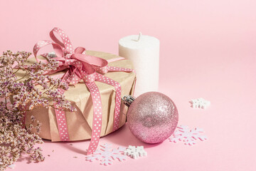 Fototapeta na wymiar Christmas or New Year gift concept in pink tones. Wrapper box, tied bow, flowers, and festive toy