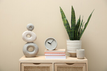 Beautiful plant in pot and different accessories on wooden commode near beige wall indoors....