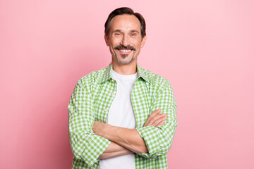 Photo of funny charming young guy dressed green plaid shirt smiling hands folded isolated light pastel pink color background