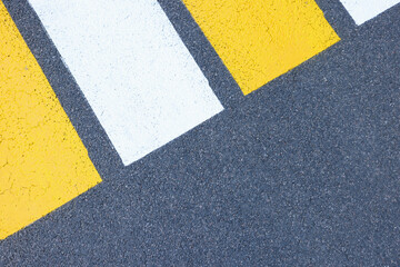 Closeup of yellow and white stripes on gray asphalt background