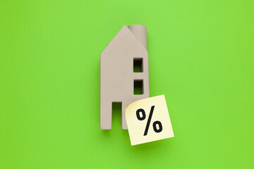 Miniature house on a green background, discount percentage when buying. Commission for real estate...