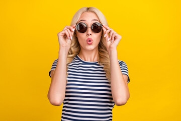 Portrait of attractive stunned girl touching specs pout lips sale new season isolated over vibrant yellow color background