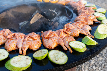 Close-up detail view of many tasty raw marinated quails and vegetables and mushrooms grilled cooked...