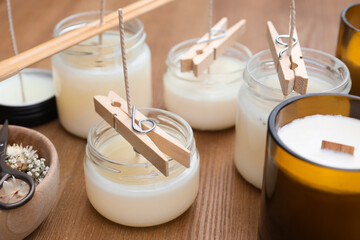 Glass jars with wax on wooden table. Handmade candles