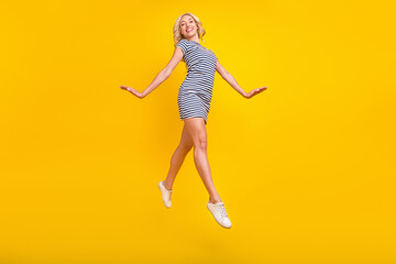 Full length body size photo woman jumping up cheerful stepping forward isolated vibrant yellow color background