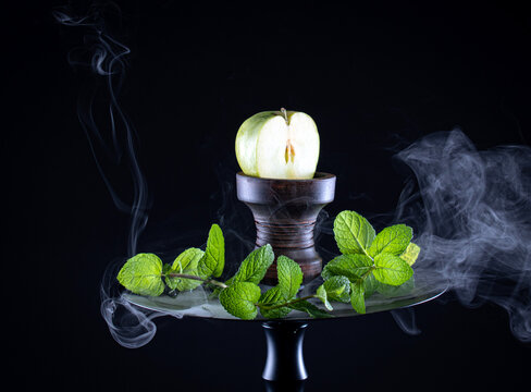 fruit hookah with tobacco, apple, mint and smoke on black background