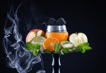 Fruit bowl for hookah with orange, apple, lime, tangerine, mint with kalaud, with coconut charcoal and smoke on a black background