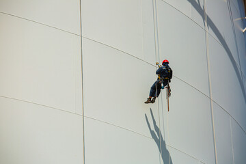 Male workers control rope down height tank rope access inspection of thickness shell plate storage tank.