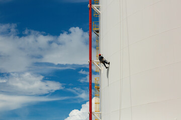 Male workers control swing rope down height tank rope access inspection of thickness pipeline and tank gas.