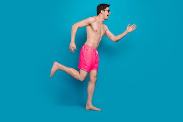 Fototapeta na wymiar Profile photo of energetic active guy run fast wear sunglass swimwear shorts isolated blue color background