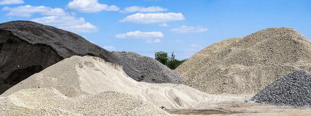 Large hills and piles of sand, gravel, crushed stone of white, gray and black color.